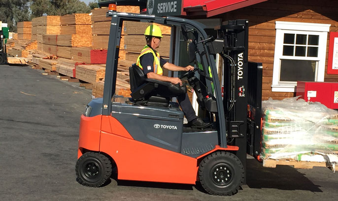 Worker in Toyota forklift carries items in lumberyard